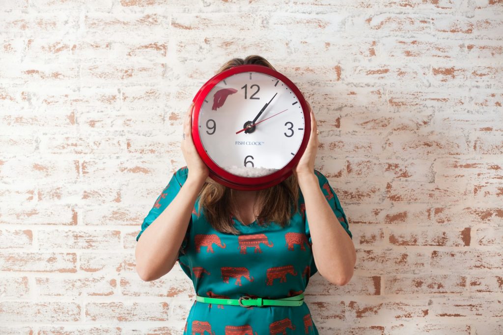 Woman with face covered by clock showing the time that done-for-you copywriting can save you 