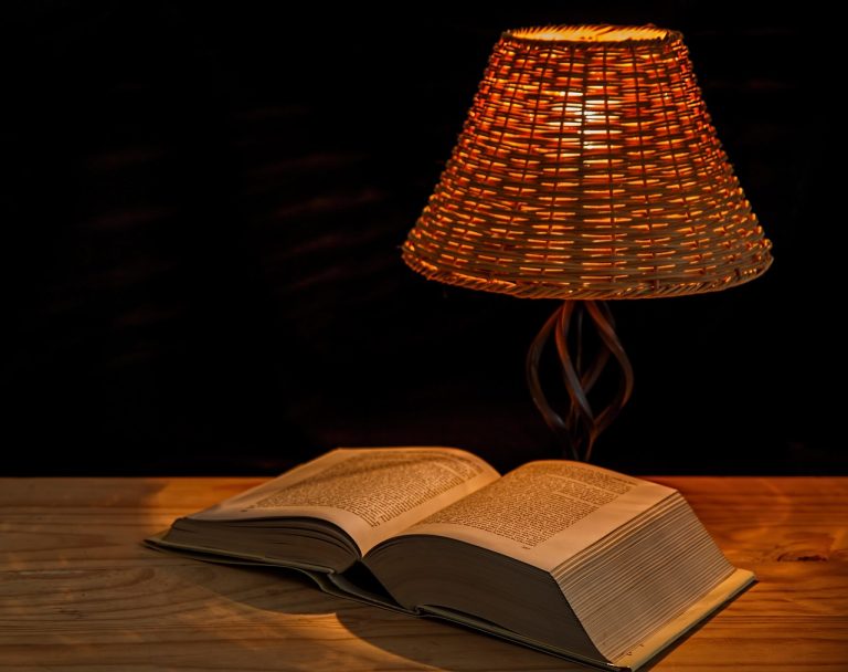 Open book under glowing lamp representing how personal voice comes alive in writing