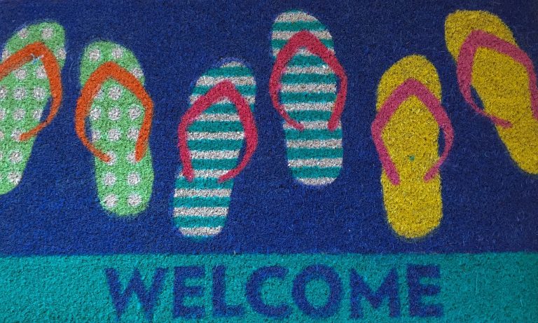 Colourful welcome mat with flip-flop prints representing consistent hospitality voice