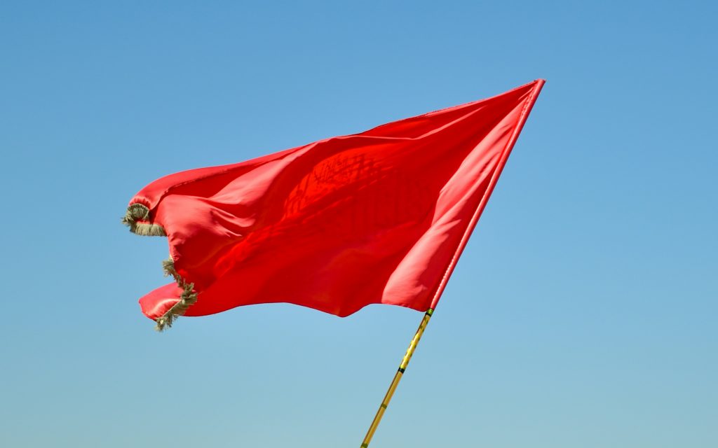 Red flag waving against blue sky representing AI copywriting red flags to watch for