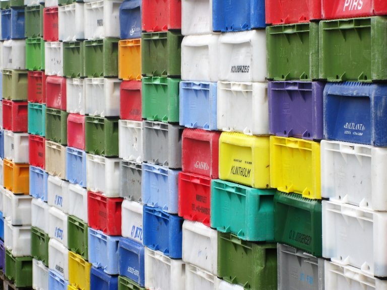 A wall of stacked plastic crates in multiple colours — orderly, uniform, and completely interchangeable